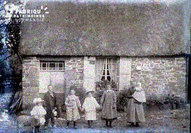 Groupe d'enfants devant une maison à toit de chaume