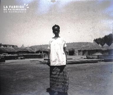 Afrique-Femme posant devant un village
