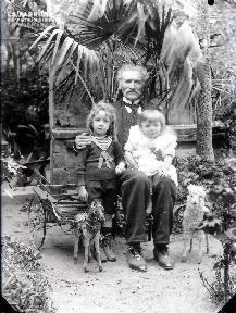 Vieil homme et ses deux petites filles devant la serre