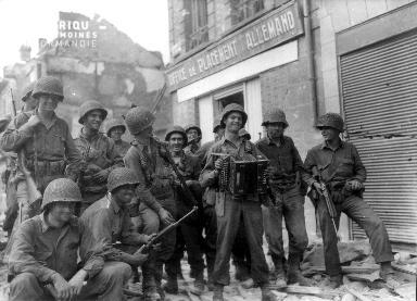 Un groupe de soldats d'infanterie américaine regroupé autour de H.C. Medley qui joue de l'accordéon