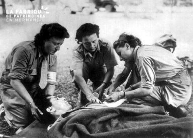 Trois Rochambelles de la Division Leclerc soignent un blessé sur un brancard.
