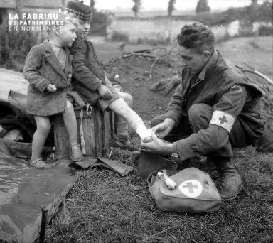 Deux enfants soignés par un soldat américain (croix rouge)