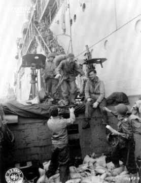 Dans le secteur d'Utah Beach, des femmes (WAC : women's Army Corps) descendent prudemment d'un paquebot par un escalier.