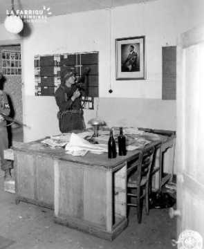 Policier militaire fixant le portrait d'Adolf Hitler à Saint-Clair-Sur-Elle