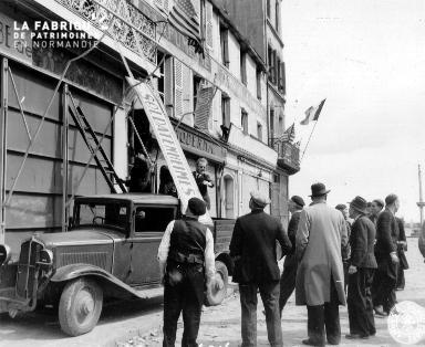 Le 28 juin 1944, des Cherbougeois décrochent un panneau allemand (inscription : SOLDATENHEIMES).