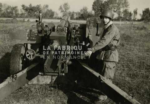 Soldat devant un canon de 105 mm M2 durant son service militaire