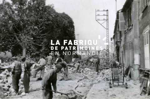 Juillet 1944 : des civils déblaient les gravats d' une rue d'Avranches, dévastée par les bombardements